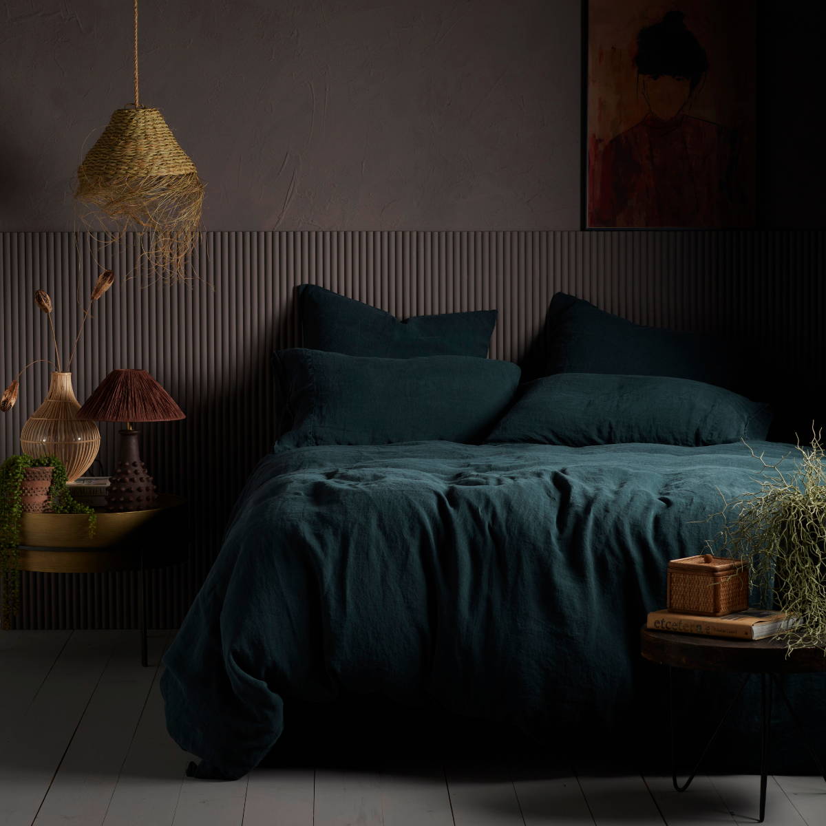 a bed made with dark teal linen bedding and a mid tone paint colour by Abigail Ahern called Cinder.