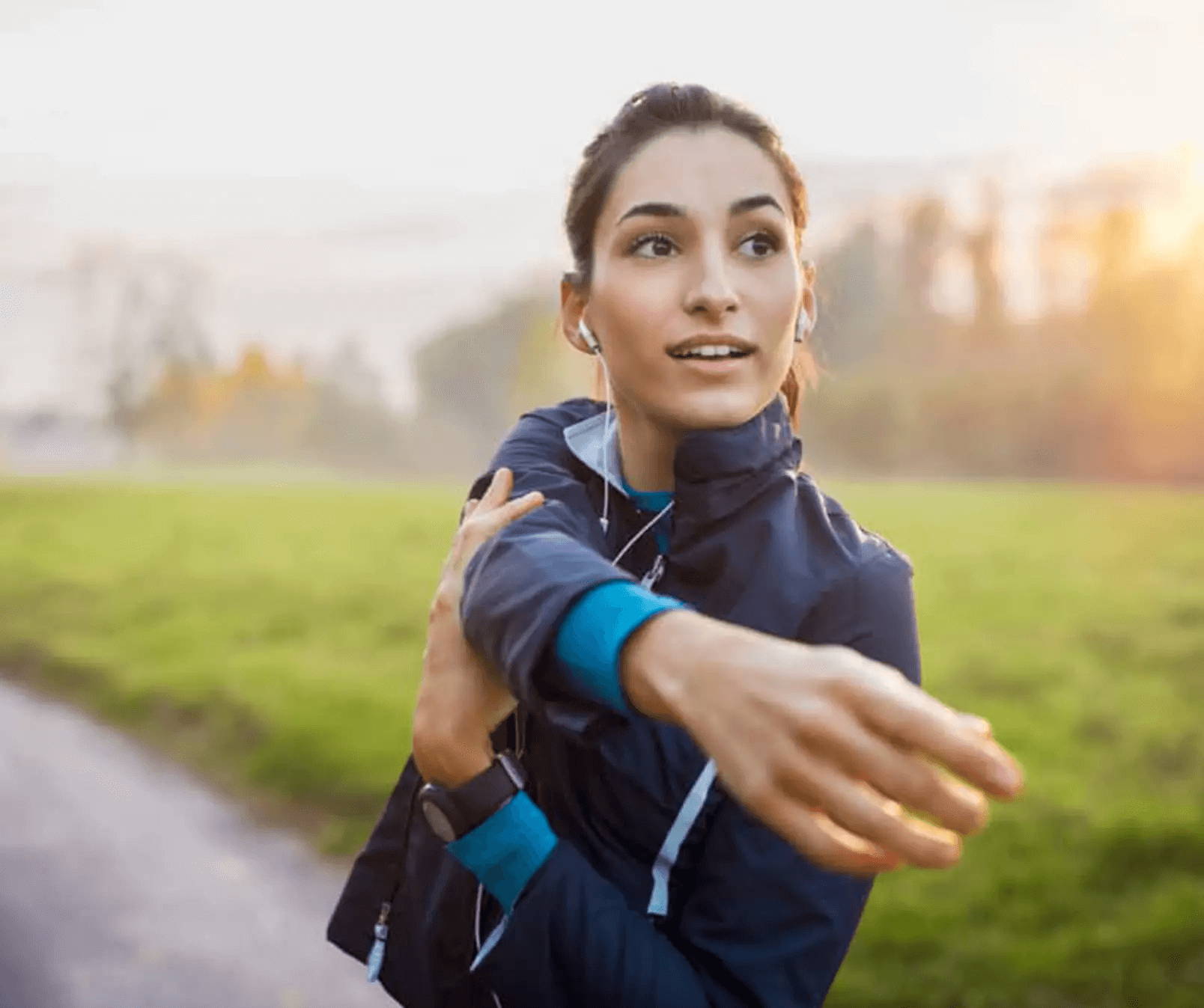 cbd for energy a dark haired woman in a blue tracksuit stretching outside