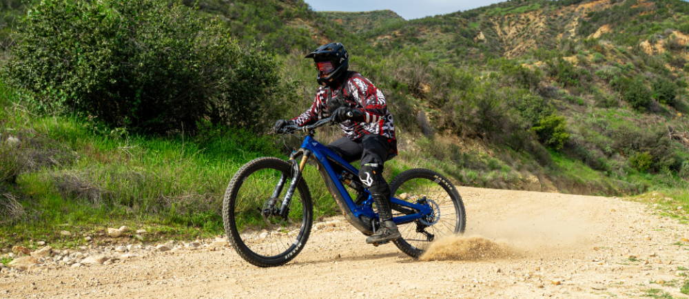 a person riding a blue full suspension electric mountain bike