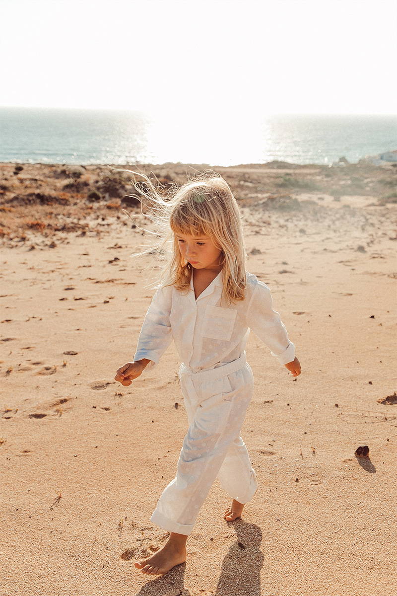 Little girl walking on the beach in her white cotton pyjamas