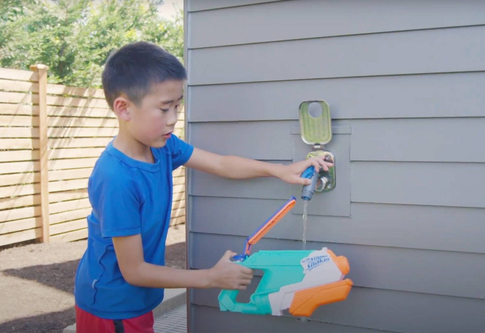 Kid connecting to Aquor House Hydrant V2+ with Removable Faucet Hose Connector filling up water gun 