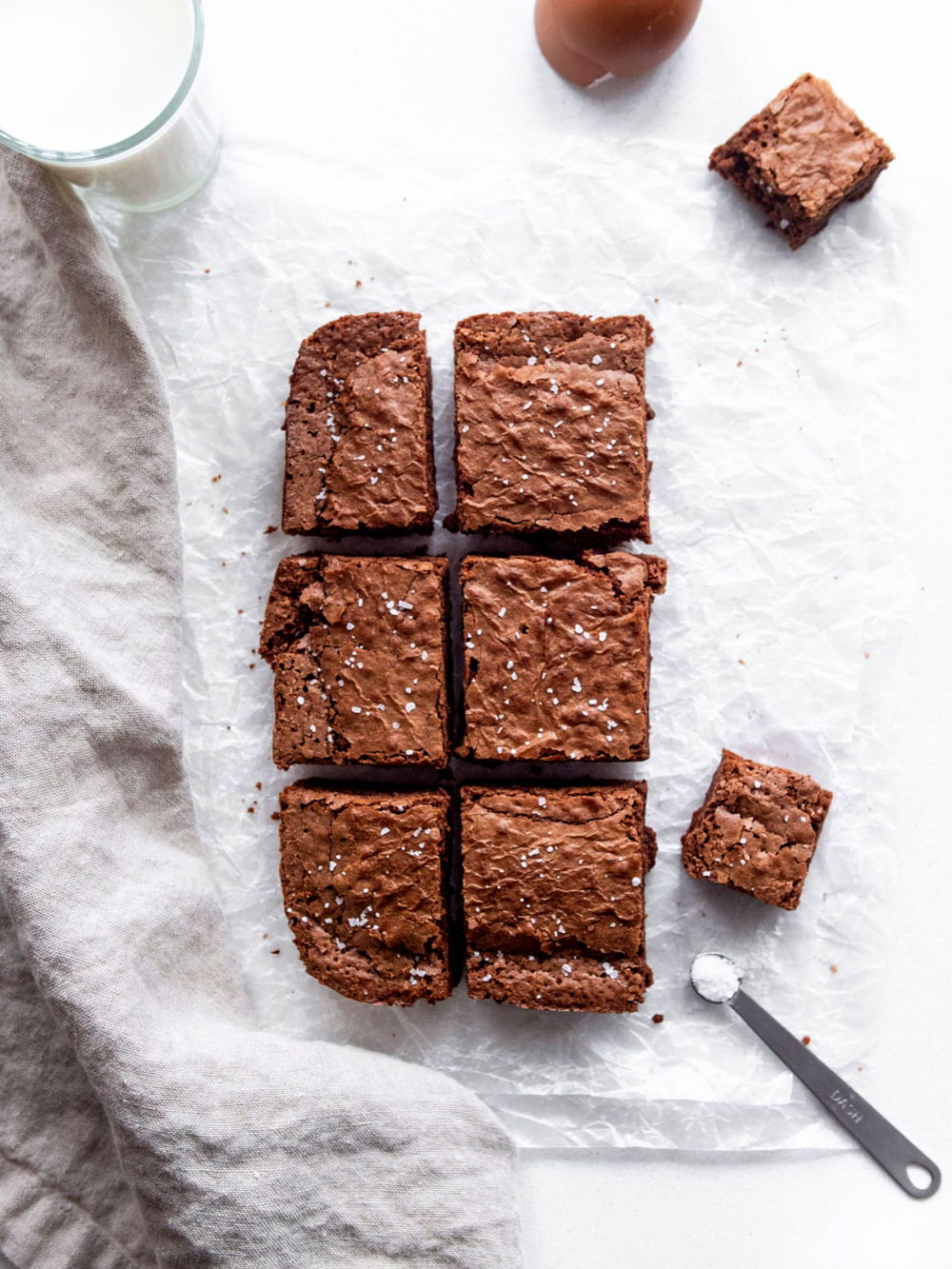 Crinkle top brownies sprinkled with salt and served with a glass of milk