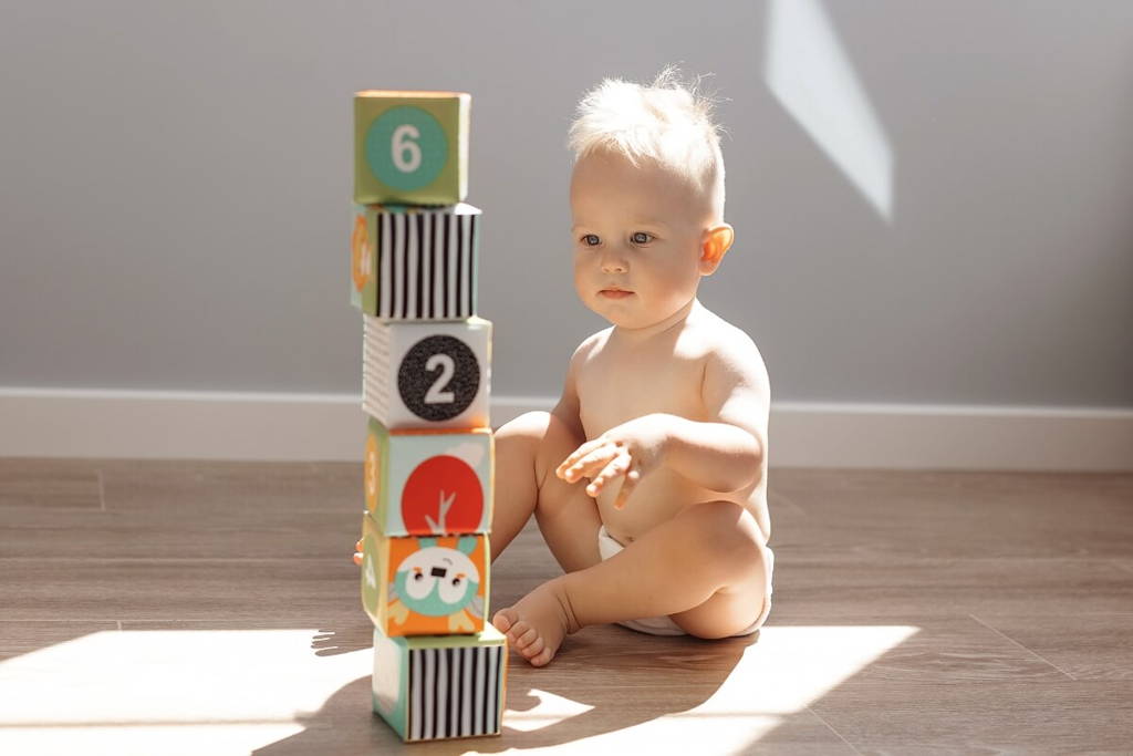 Baby boy playing with colorful blocks that have numbers on them.