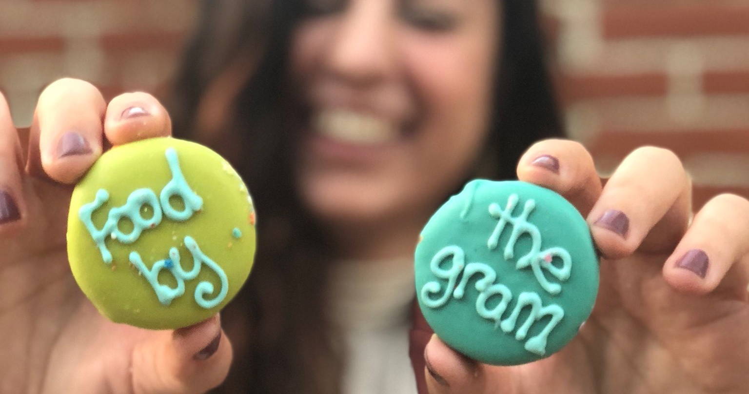 A woman holds cookies that say "food by the gram"