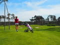 Woman pushing a golf push cart with bag on sunny course