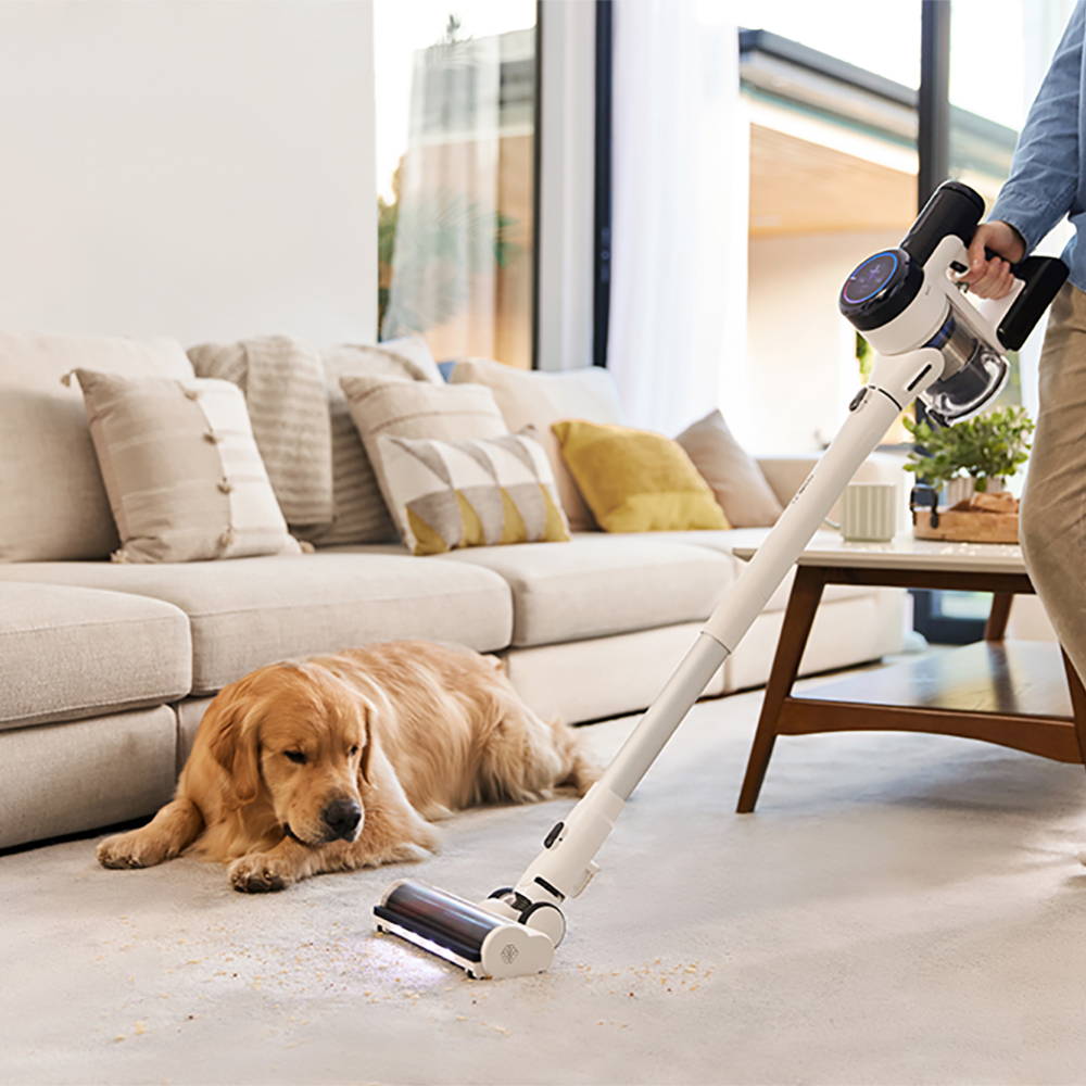 a dog lying on the floor with a vacuum cleaner