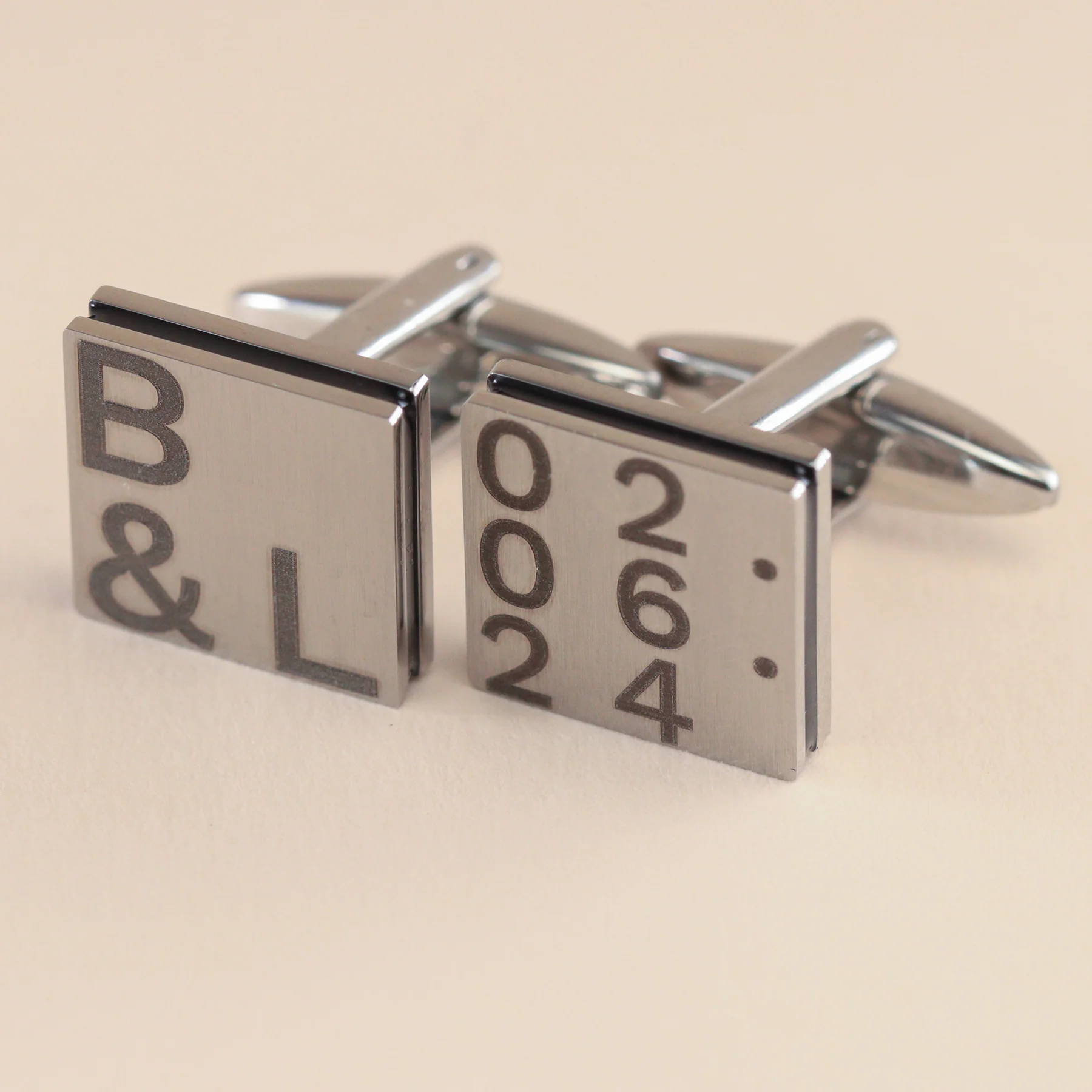 Close up image of a pair of polished stainless steel cufflinks with a Mandolorian and Grogu illustration engraved on the face.