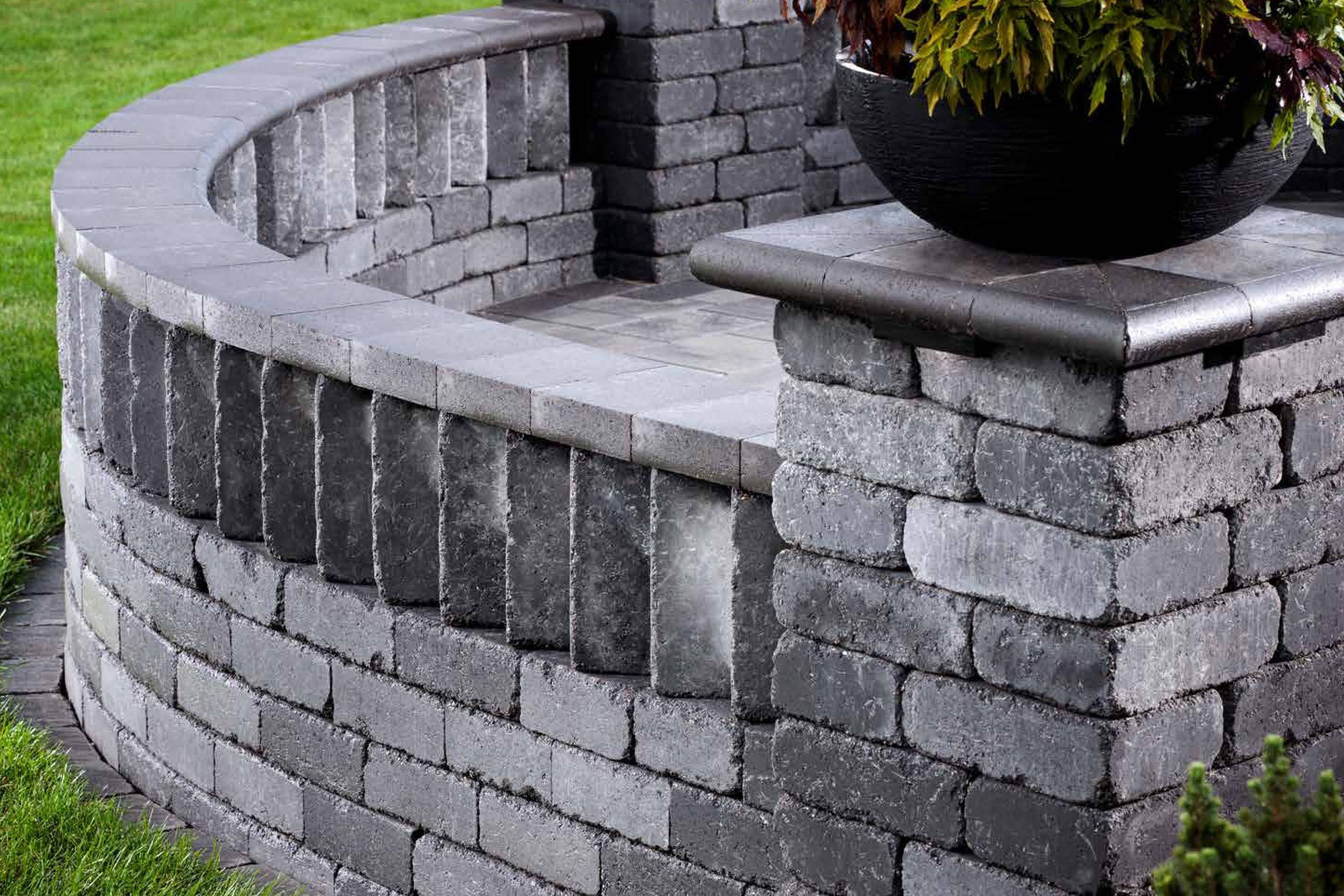 Rounded retaining wall with a unique cap stone design and pillars made with Weston Wall Corner Bricks