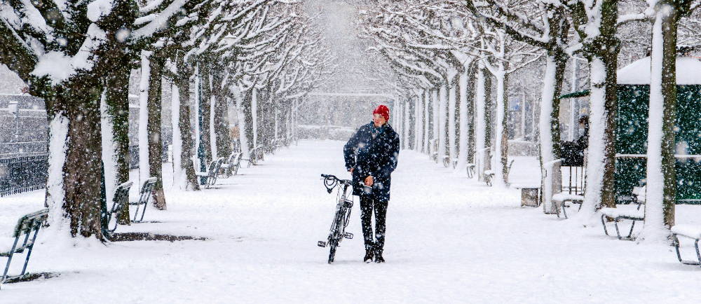 Man walking his bike in snow