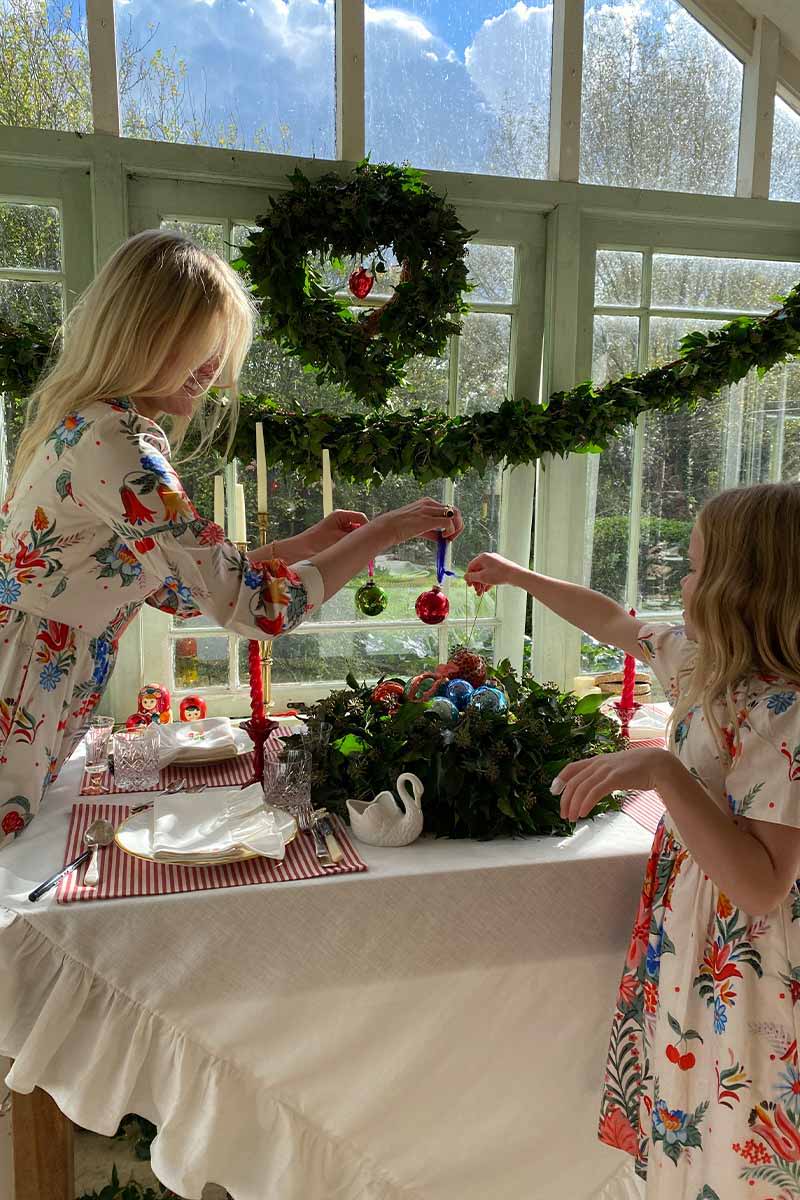 Ella Ringner Sets the festive table with her daughter while they both match in YOLKE Dresses