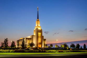 Twin Falls Temple glowing against a blue and orange sky. 