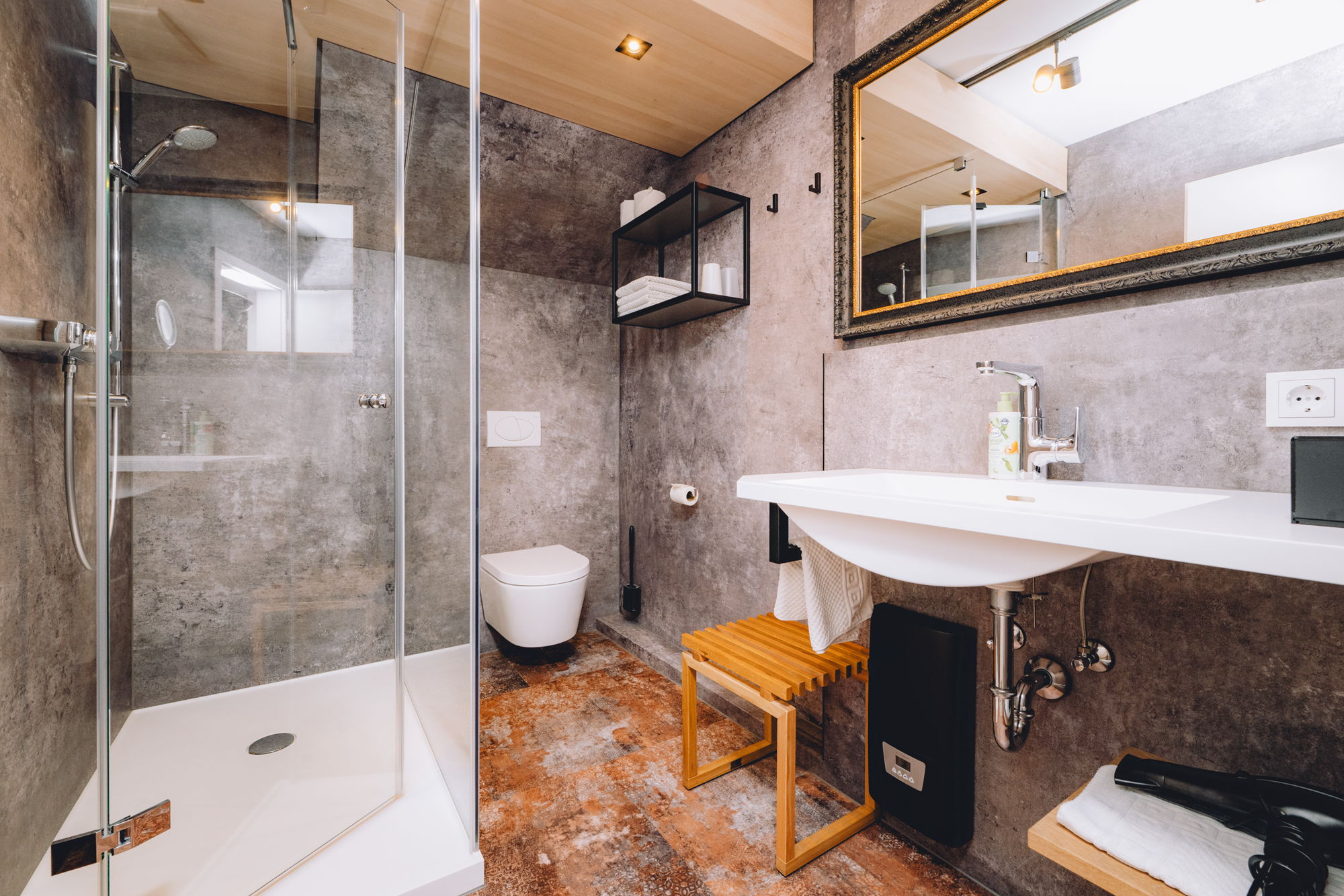 Ein modernes Badezimmer mit Steinwänden, schlankem Waschbecken, einem eingerahmten Spiegel und einer großen Dusche mit Glaswänden.