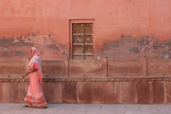 A person in a pink outfit walking past a similarly colored building