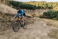 Cycliste sur velo gravel descendant un sentier vallonné