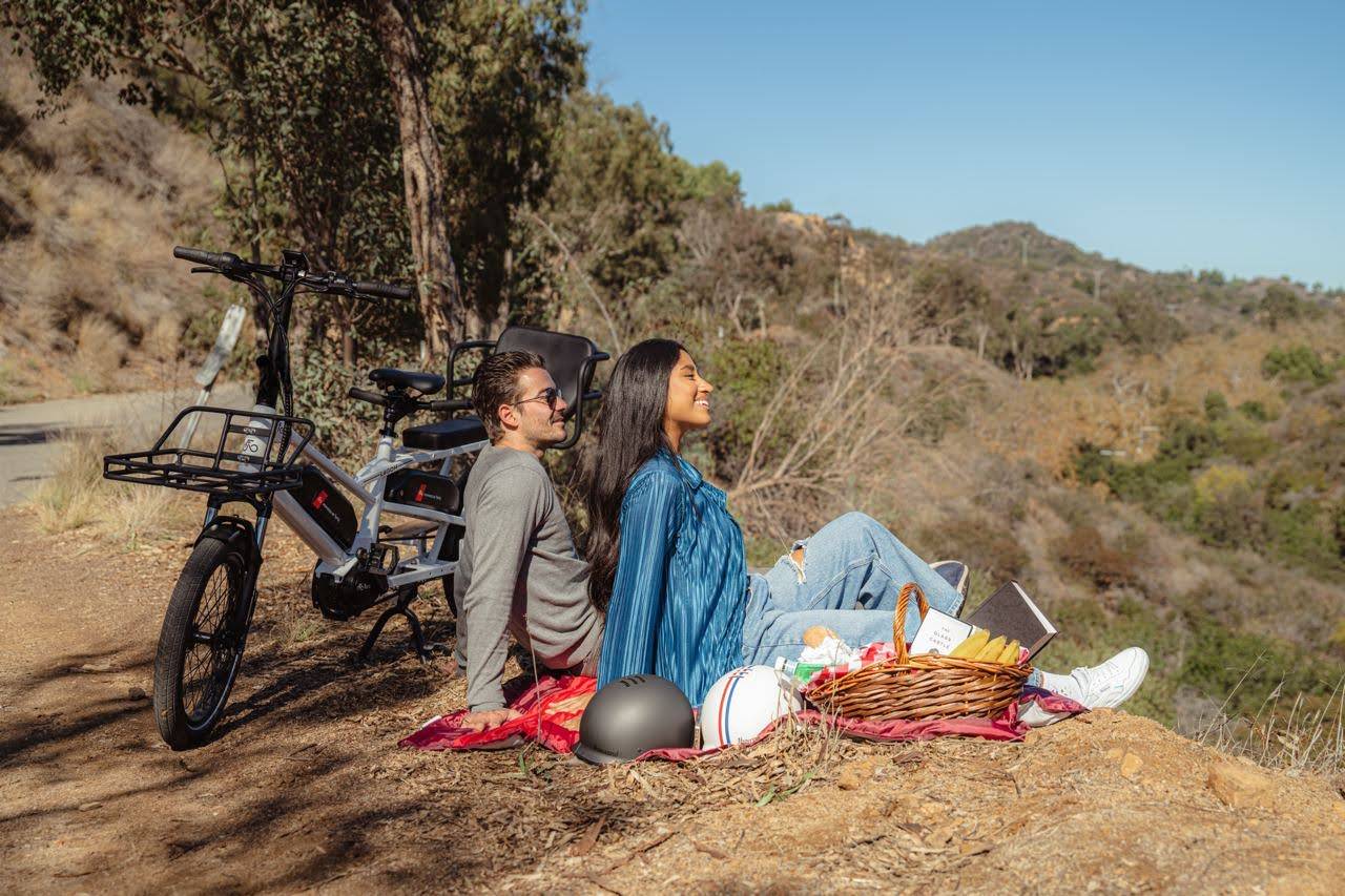 Un couple se promenant avec un vélo électrique longtail pour faire un pique-nique avec leurs enfants