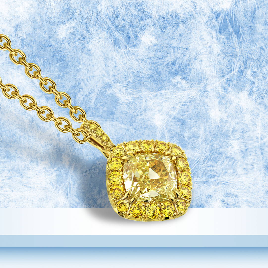 Cushion cut yellow diamond pendant with yellow diamond accents in 18k yellow gold on a blue background.