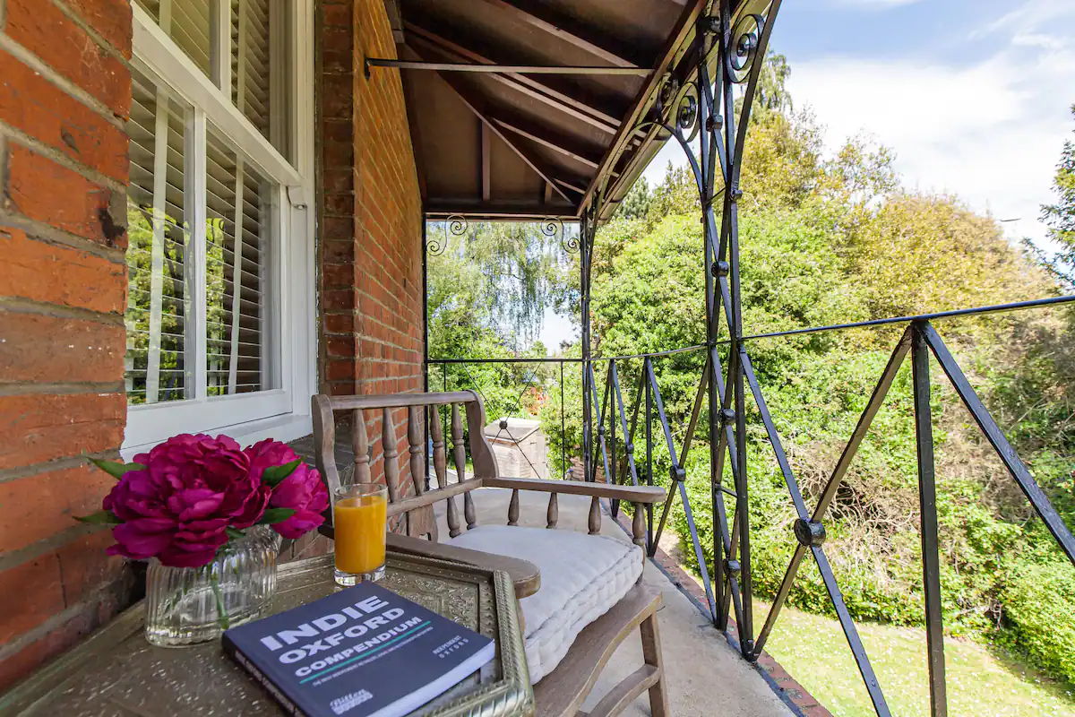 Balcony view from the property - Table with fruit juice and book facing trees and grass