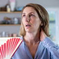 Woman using paper fan as she has hot flashes