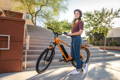 Femme avec son nouveau vélo électrique à l'entrée d'un immeuble
