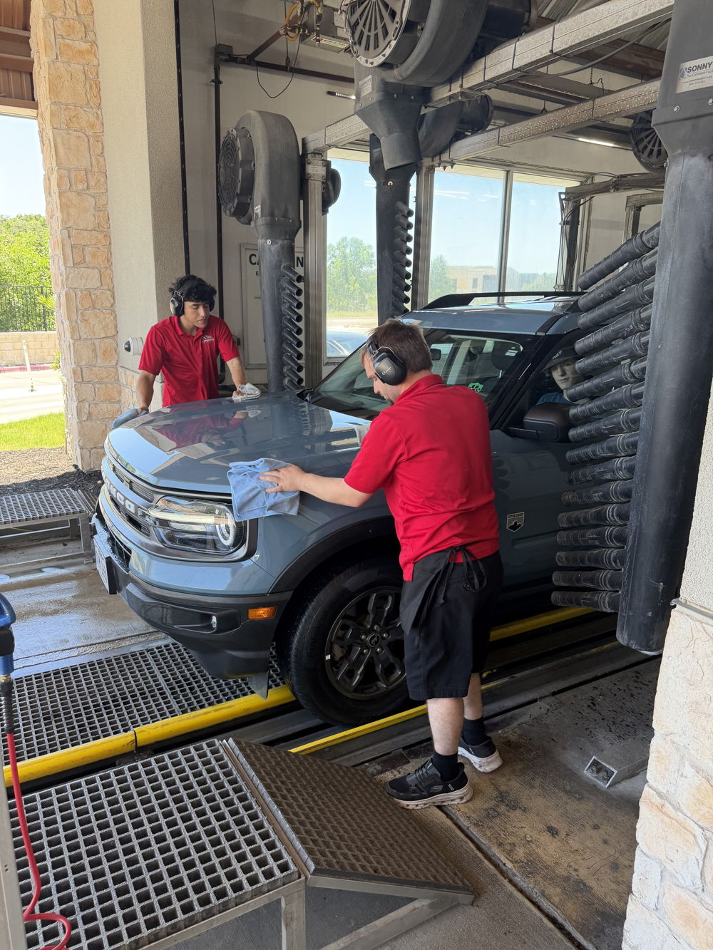 All American attendant hand towel-drying a vehicle at the tunnel exit