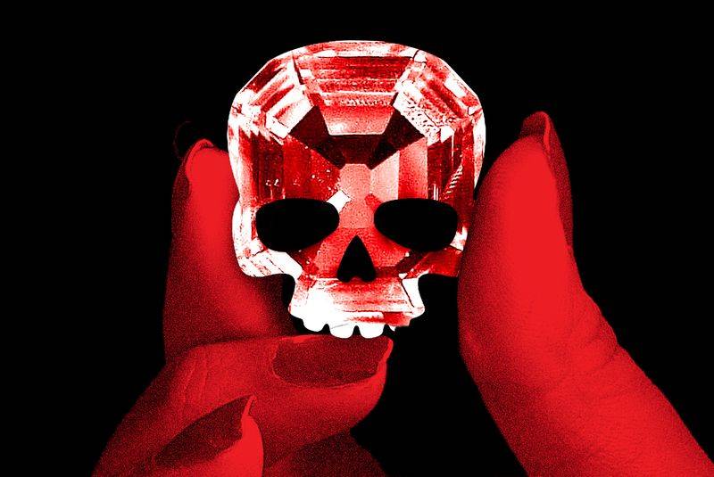 An illustration of a hand holding a diamond that is shaped like a skull.