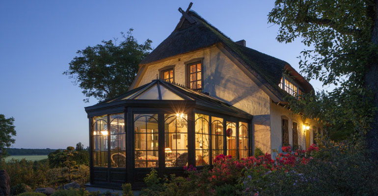 Orangerie vitrée à petits bois illuminée au crépuscule