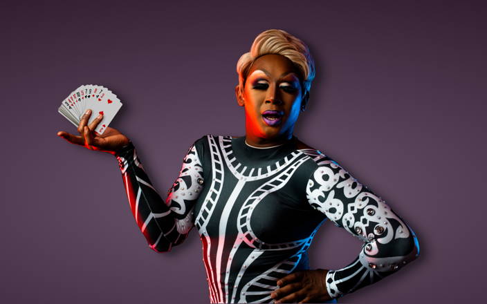 A drag queen striking a pose and holding a fanned out deck of cards for Confetti's Virtual Casino Team Building