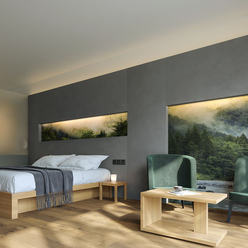 Zimmer mit Bett und 2 Stühlen vor grauer Wand