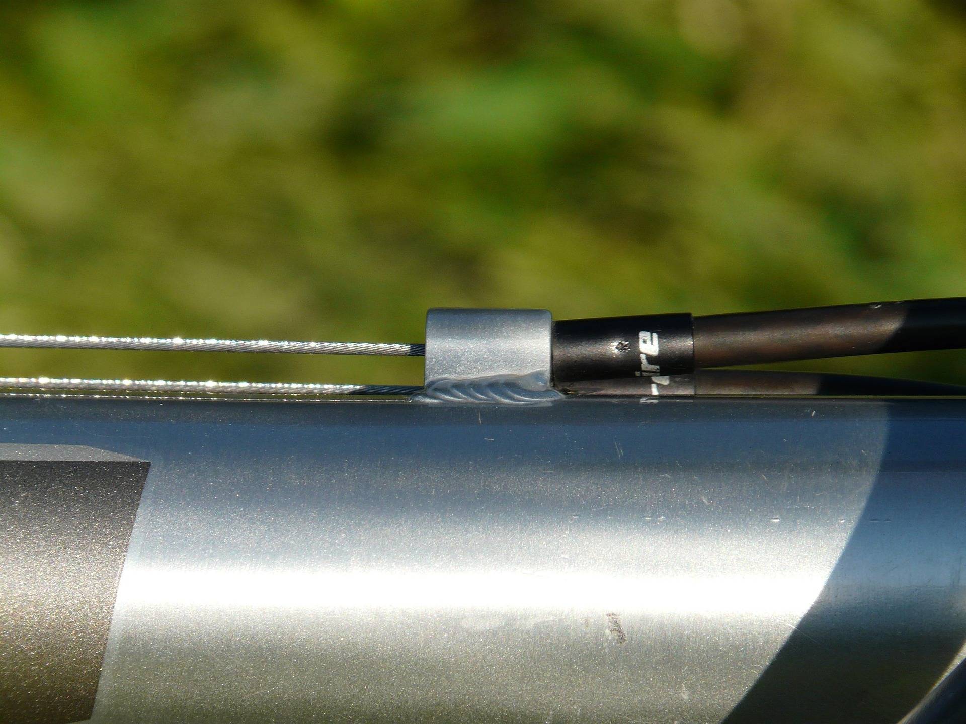 Câble intérieur de dérailleur sortant de sa gaine le long du cadre d'un vélo