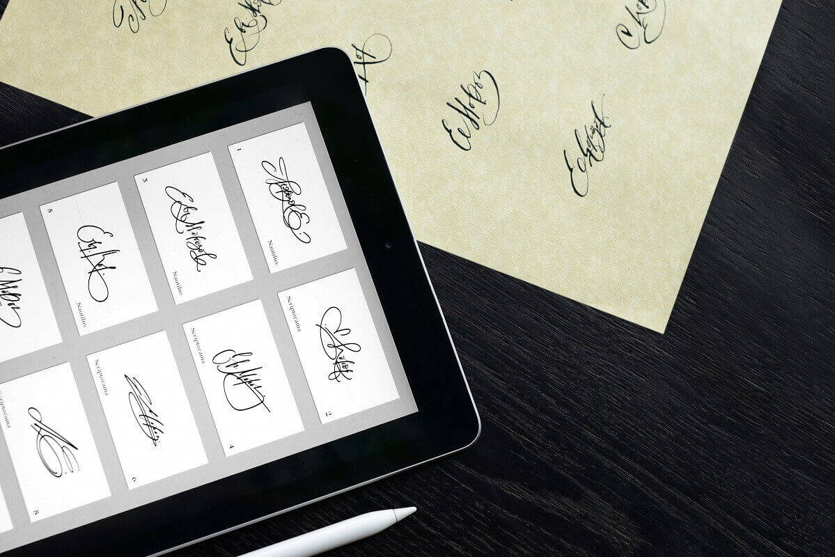 Tablet und Blatt Papier mit verschiedenen Unterschriften