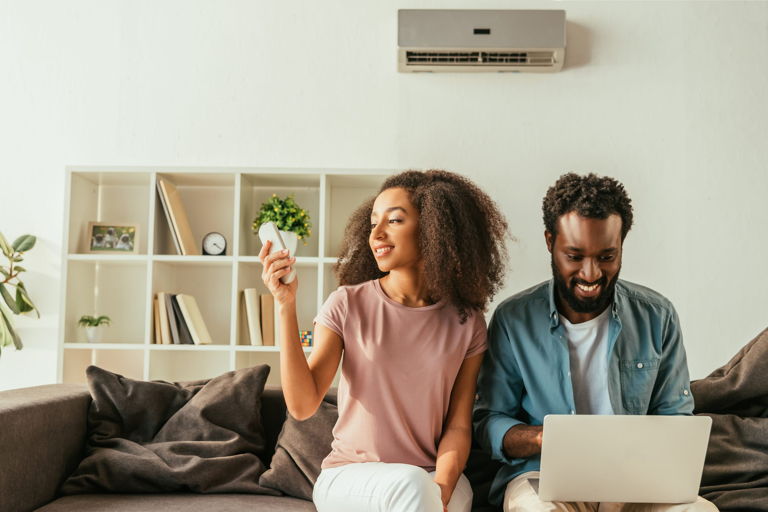 couple on couch using remote to control mini split