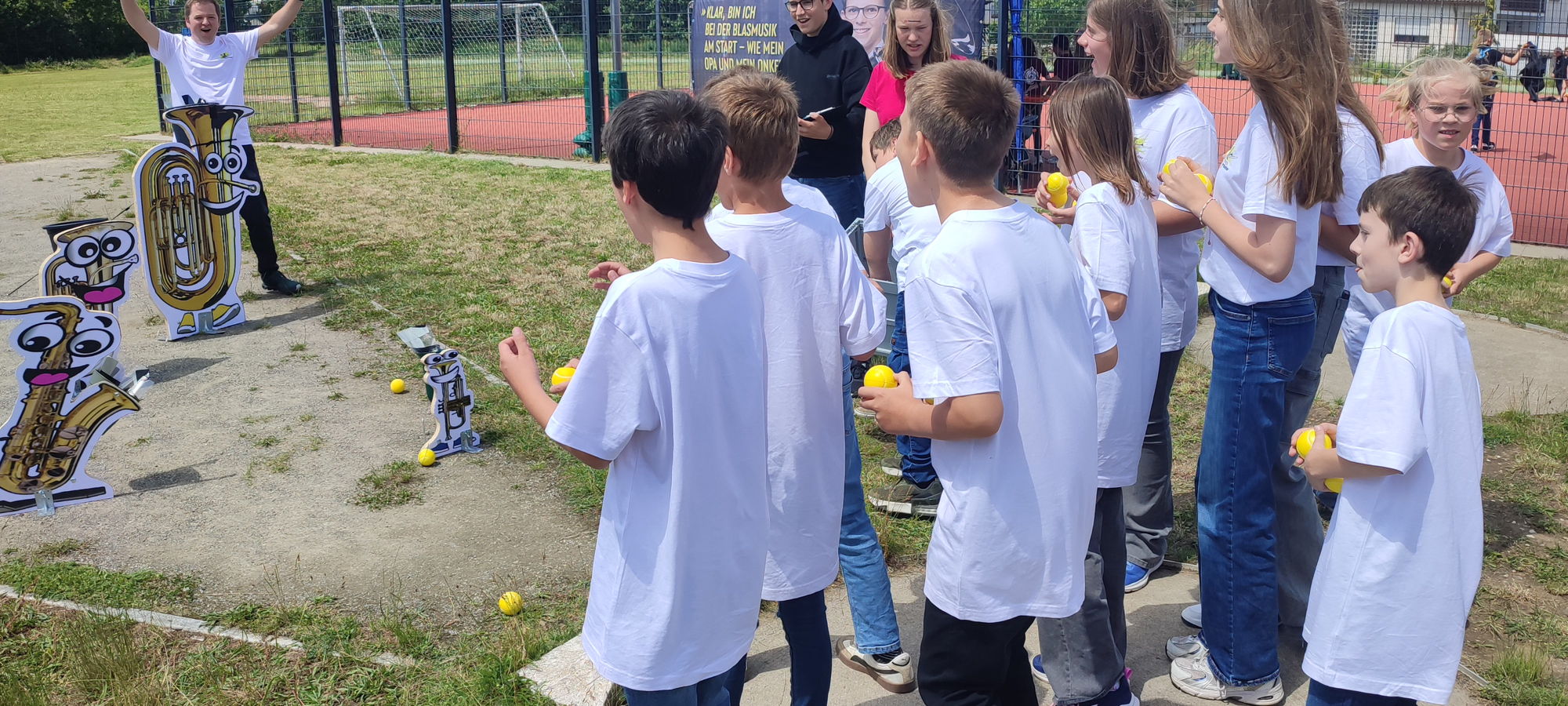 Einige Kinder in gleichen T-Shirts spielen ein Wurf-Spiel. 