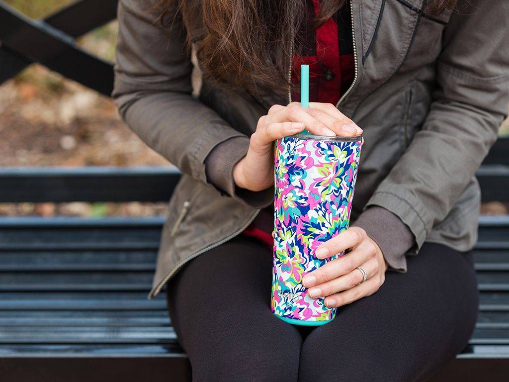 A woman holds a colorful Swig tumbler