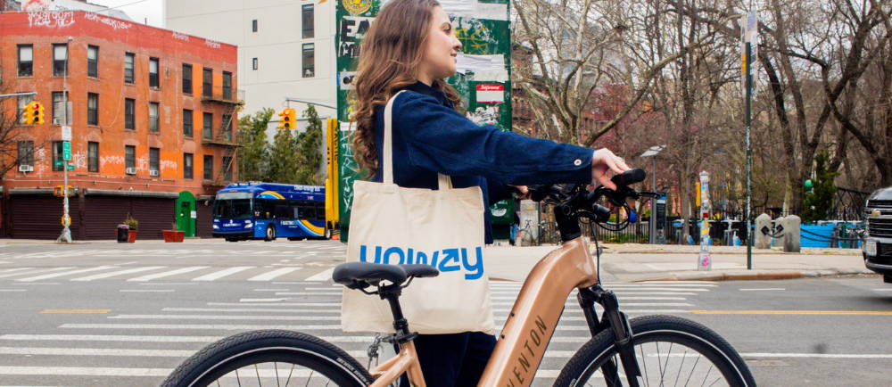 Woman walking alongside electric bike with Upway tote