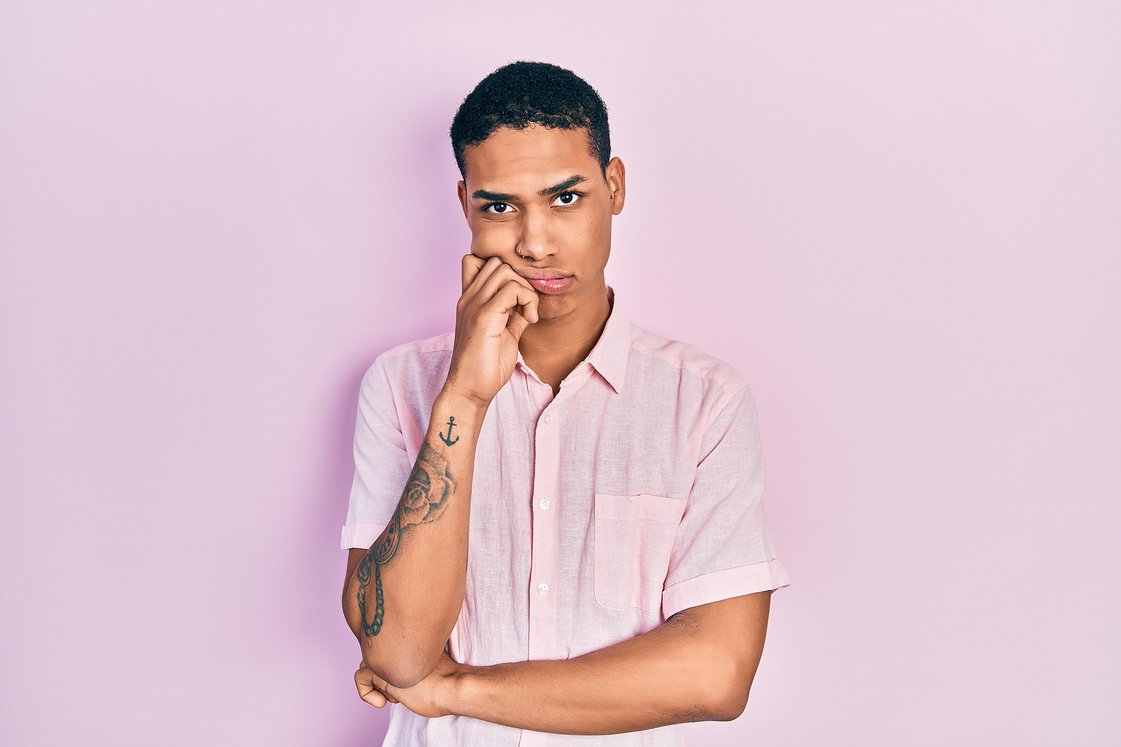 Young african american guy wearing casual clothes thinking looking tired and bored with an arm to his chin.