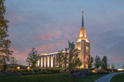 Evening photo fo the Twin FAlls Temple, caputring glowing windows against a pink and purple sky. 