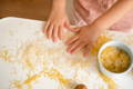 Child exploring rice and pasta textures during summer themed sensory play.