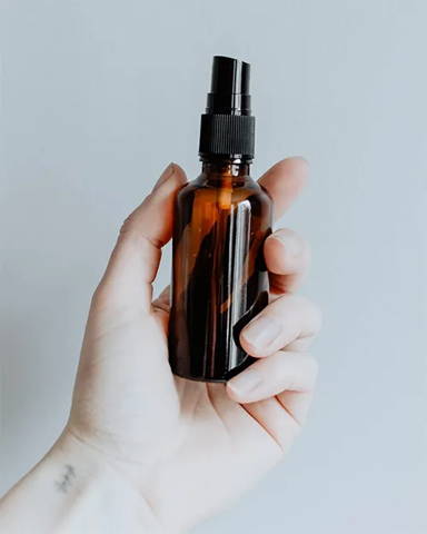 Amber colored small spray bottle in glass