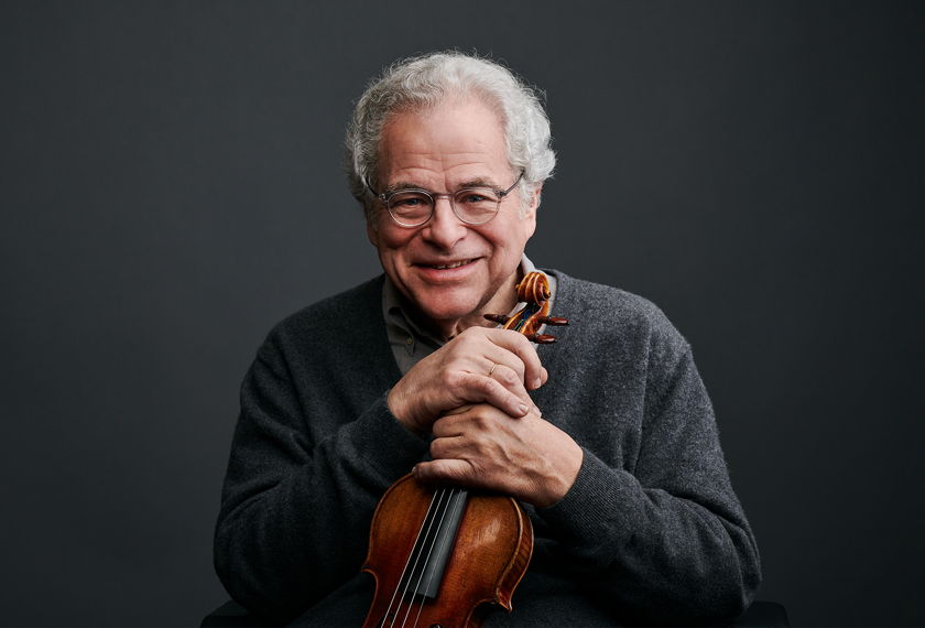 Close up portrait of Itzhak Perlman smiling and holding a violin. 