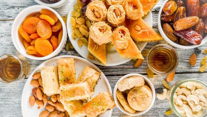 Set various Middle Eastern Arabian sweets - Turkish baklava, knafeh (kunaf), nuts, dried fruits and seeds. White wooden background
