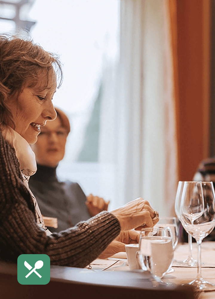 Ältere Frau unterhält sich in einem lauten Restaurant mit Wellue OTC-Hörgeräten im sprachverstärkenden Restaurantmodus