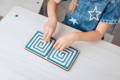 Little girl playing with a wooden maze toy. 