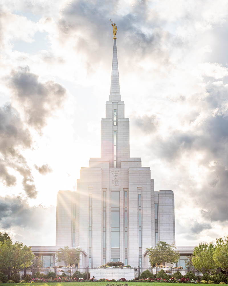 LDS art vertical photo of the Oquirrh Mountain Temple with sun beams shining out from behind.