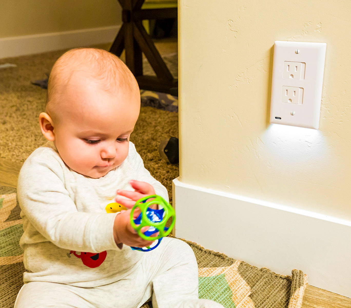 Baby playing with a toy and sitting next to the SafeLight night light for kids