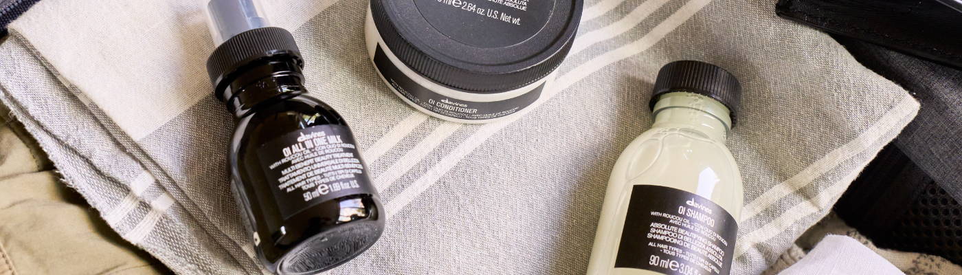 mini OI shampoo, OI milk, OI conditioner inside a packed suitcase