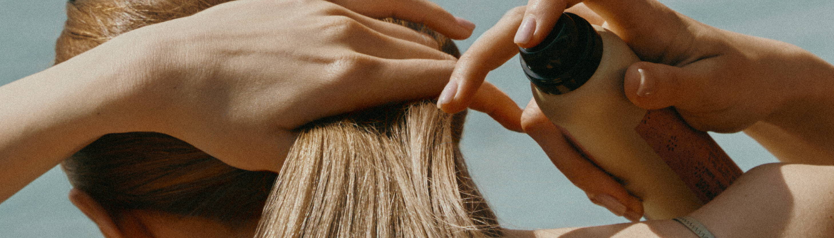 Blonde woman putting her hair into a ponytail using Davines This is a Shimmering Mist