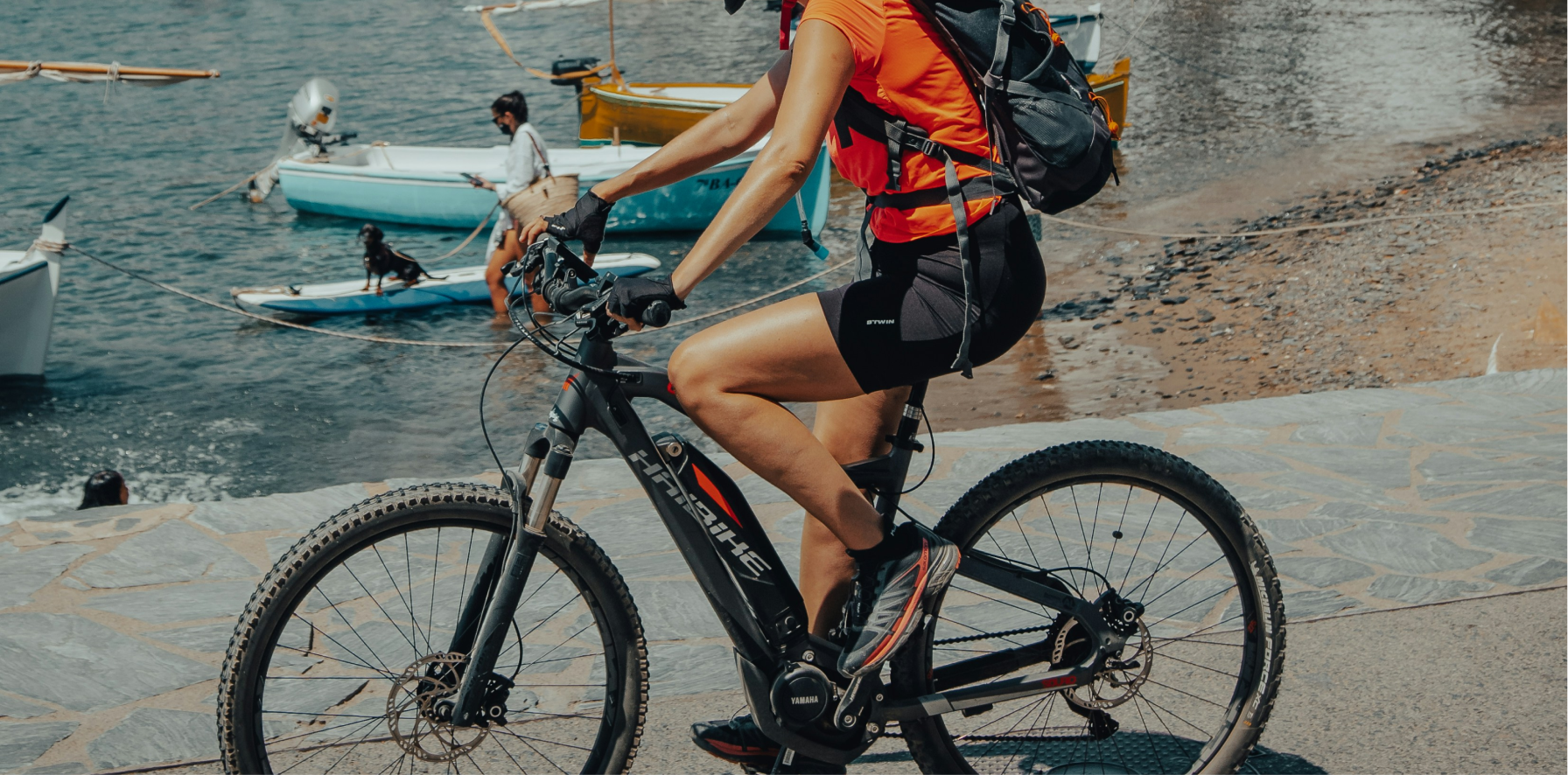 mujer en bicicleta electrica con el mar de fondo en verano