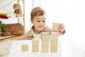 Boy playing with wooden blocks in a playroom.