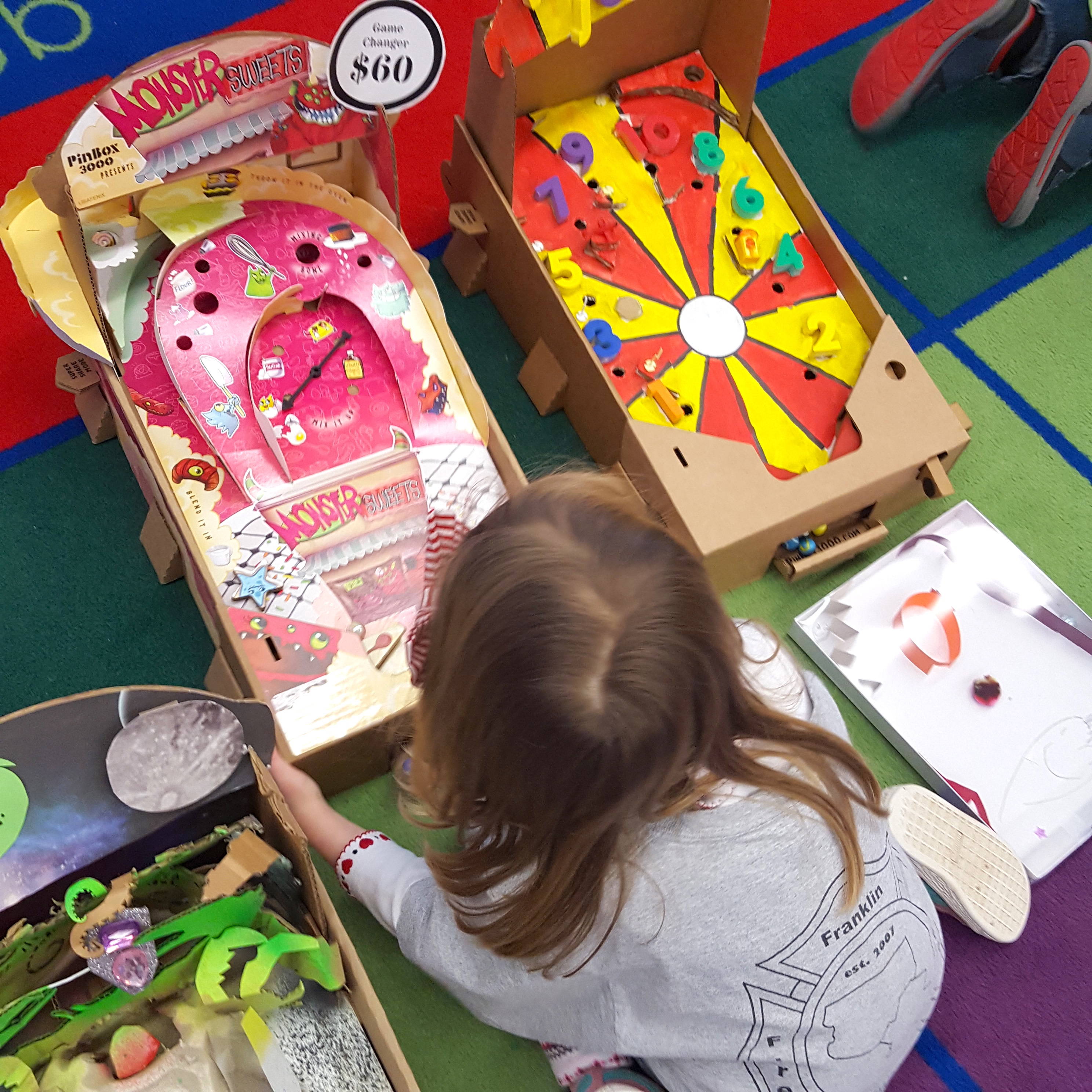 A student has fun with PinBox 3000 cardboard pinball games.