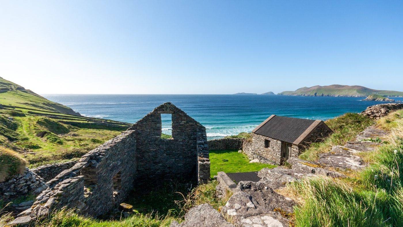 Ireland scene of green farmland and stone foundation ruinsoverlooking the ocean